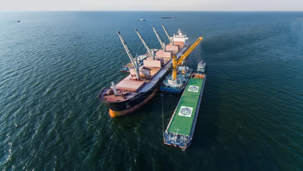 A bulk carrier and a barge performing cargo transfer operations at sea, representing the significance of precise assessments in cargo damage survey reports and appeals.